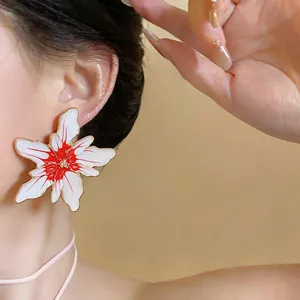 Macro detail of large white and red enamel flower stud earrings with silver needle