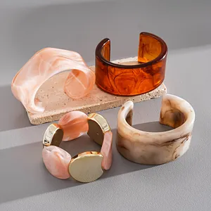 Vue détaillée de joncs en acrylique marbré et d'un bracelet élastique à maillons dorés