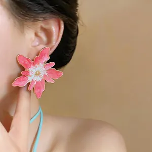 Detailed macro shot of an elegant pink and white enamel flower earring worn on ear
