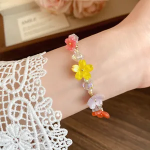 Primo piano di un braccialetto di perline con fiori in resina colorata sul polso
