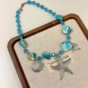 Detailed view of beach-style necklace with blue beads and silver starfish charms