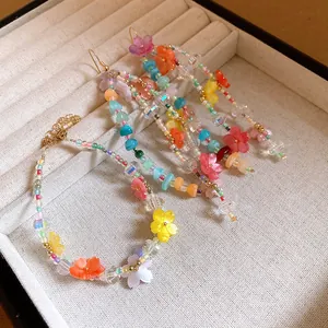 Vista dettagliata di bracciale e orecchini colorati con fiori in resina e perline