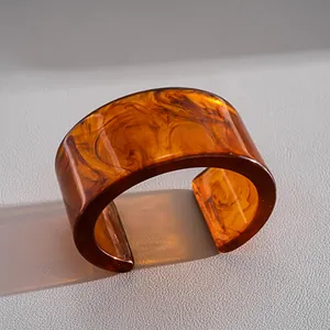 Gros plan détaillé d'un large bracelet en acrylique ambré avec texture écaille de tortue
