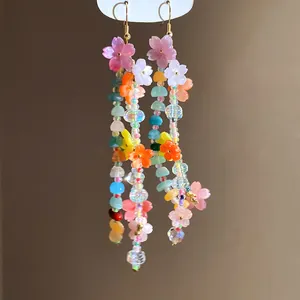 Primo piano di orecchini pendenti con perline colorate e ciondoli a fiore in resina