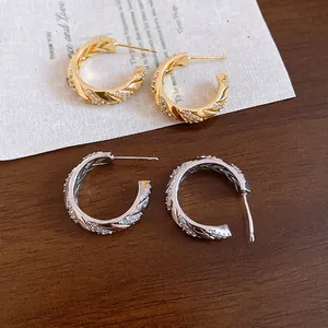 Close-up detail of gold and silver plated hoop earrings with textured wheat ear design