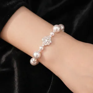 Elegant pearl bracelet with a sparkling zircon flower centerpiece worn on wrist