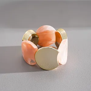 Vue détaillée montrant la texture marbrée de l'acrylique et des disques dorés du bracelet