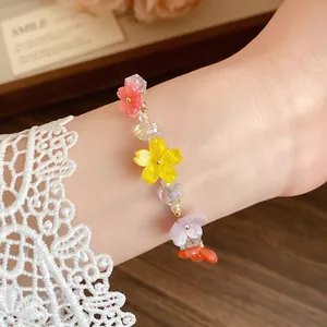 Dettaglio di un braccialetto di perline colorate in resina con fiori al polso con pizzo
