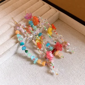 Dettaglio macro di orecchini a nappa con perline multicolori e fiori in resina