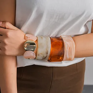 Gros plan de quatre bracelets joncs en acrylique avec motifs marbre et ambre au poignet