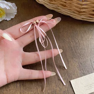 Vue détaillée des boucles d'oreilles à nœud en ruban rose avec aiguilles en argent