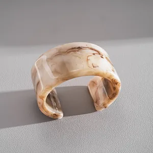Détail d'un large bracelet manchette en acrylique avec texture marbre sur fond gris