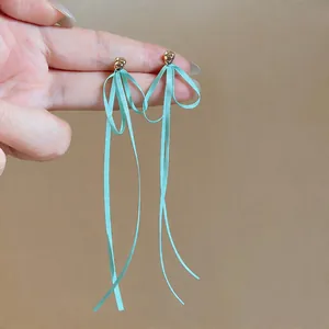 Vue détaillée de longues boucles d'oreilles nœud en ruban vert menthe.