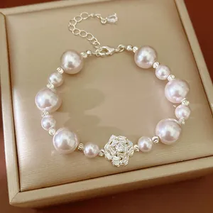 Close-up of pink pearl bracelet with zircon flower charm on jewelry box