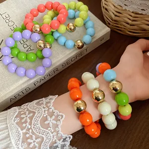 Close-up detail of colorful chunky round bead bracelets featuring metallic gold accents