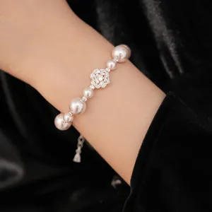 Elegant pearl bracelet with a central zircon-inlaid flower detail on a model's wrist