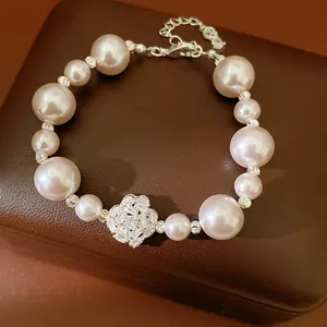 Close-up of elegant pearl beaded bracelet with sparkling zircon flower charm