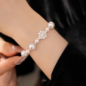 Close-up of a luxurious pearl bracelet with a sparkling zircon-studded flower charm.
