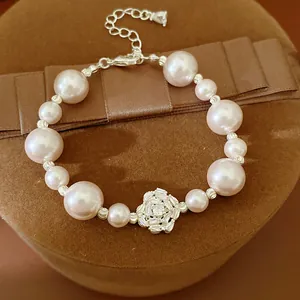 Close-up detail of a elegant pearl bracelet with a shimmering zircon flower charm