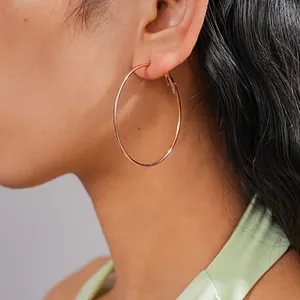 Detailed view of large minimalist rose gold hoop earring worn for a high-end look
