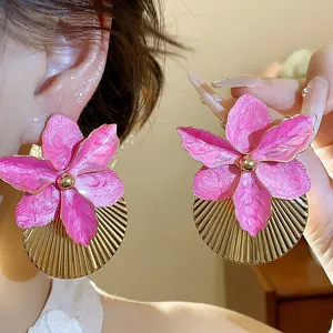 Dettaglio degli orecchini a fiore rosa con dischi in oro pieghettati e perno argento.