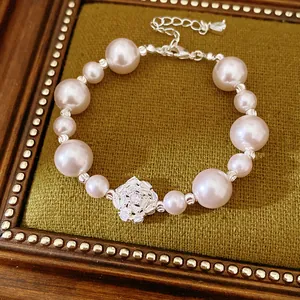 Detailed view of an elegant pearl bracelet with a zircon floral centerpiece on a velvet tray