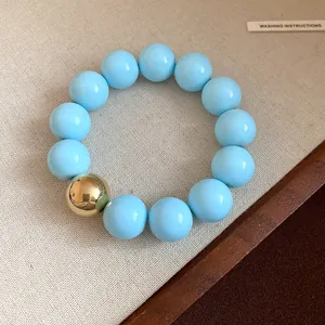 Close-up of chunky blue beads and a single shiny gold bead on a stylish geometric bracelet