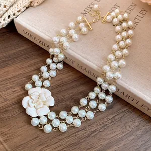 Detail of multi-layered glass pearl necklace with white enamel camellia flower