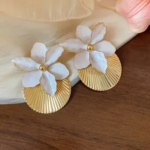 Primo piano di orecchini a fiore in smalto bianco con base rotonda plissettata oro