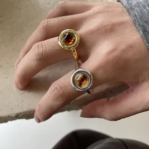 Detail shot of gold and silver minimalist resin rings with brown stones on hand.