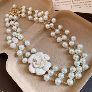Detail shot of a French vintage multi-layer pearl necklace with white enamel flower charm