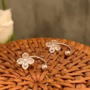 Elegant silver hollow flower ear cuffs with delicate filigree details on rattan.