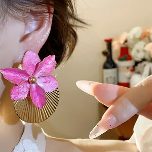 Dettaglio orecchini fiore smaltato rosa con disco dorato plissettato e ago argento