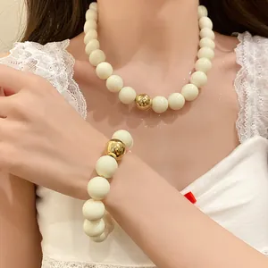 Fashionable large cream and gold beaded necklace and bracelet jewelry set on model