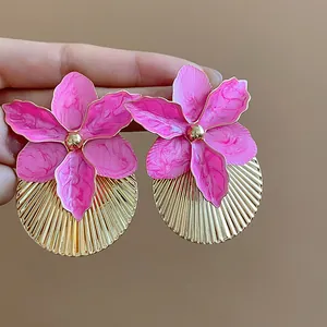 Primo piano di orecchini a fiore rosa con base rotonda plissettata dorata dettagliata
