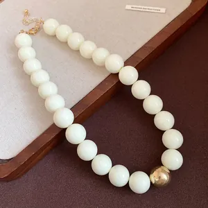 Close-up of chunky cream-white round bead necklace with a large gold accent bead