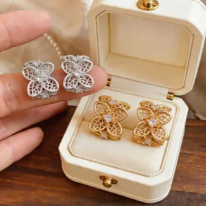 Vista detallada de pendientes de flores huecas en oro y plata adornados con circonitas brillantes.