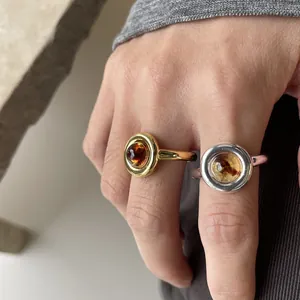 Detail shot of minimalist Maillard style resin round open rings in gold and silver.