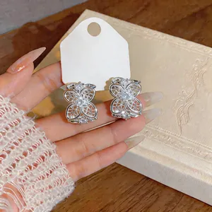 Detalle de pendientes de flor calada en plata con brillantes piedras de circonita