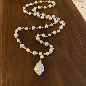 Detailed view of vintage Baroque imitation pearl necklace with irregular gold-tone pendant