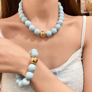 Detail of chunky light blue beaded necklace and bracelet set with gold accent bead