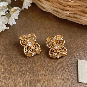 Primer plano de pendientes de flores caladas doradas con brillantes circonitas claras