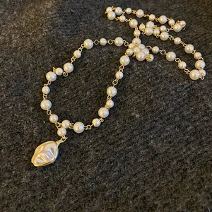 Detailed view of baroque pearl necklace with irregular pendant on grey knit background