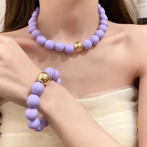 Fashionable chunky purple and gold round bead necklace and bracelet set on model