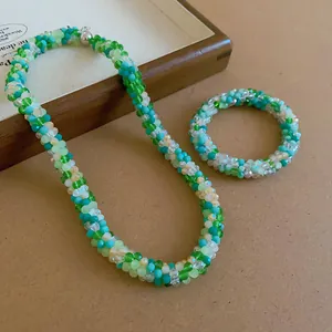 Detail showing handmade woven crystal beaded necklace and bracelet set in vibrant green tones.