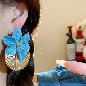 Primo piano di orecchini a fiore blu con ventaglio dorato a pieghe