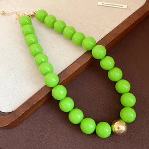 Detail shot of a chunky bright green beaded necklace with a statement gold bead