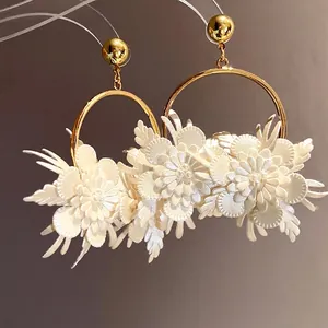 Eleganti orecchini a cerchio dorati con fiori in pelle bianca a strati e dettagli in perla.