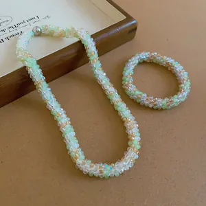 Detailed view of woven crystal beaded necklace and bracelet set in soft green and amber