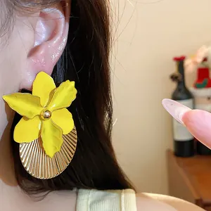 Primo piano dei orecchini a fiore giallo con design circolare plissettato dorato.